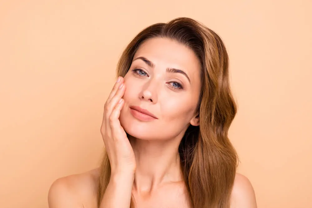 Serum dropper held above an open palm against a soft neutral background